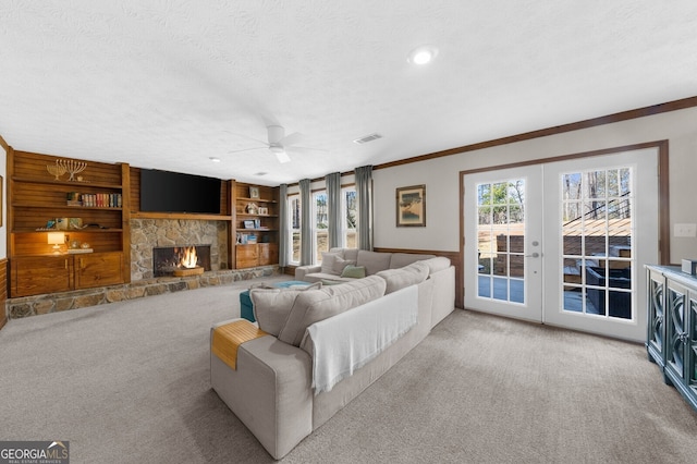 carpeted living room featuring visible vents, built in features, a fireplace, french doors, and a textured ceiling