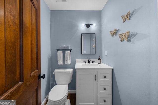 half bathroom with vanity, toilet, and visible vents