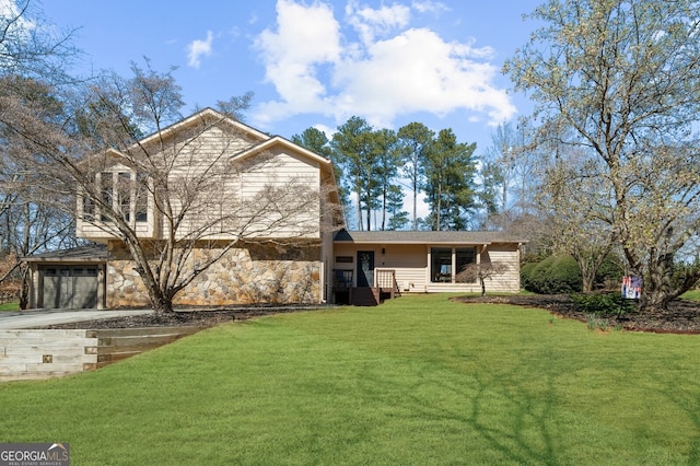 back of property featuring a yard, stone siding, and driveway