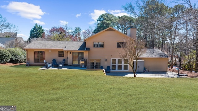 rear view of house featuring french doors, a patio, a lawn, and a chimney