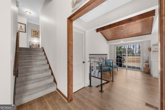 stairway featuring visible vents, baseboards, wood finished floors, and wooden ceiling