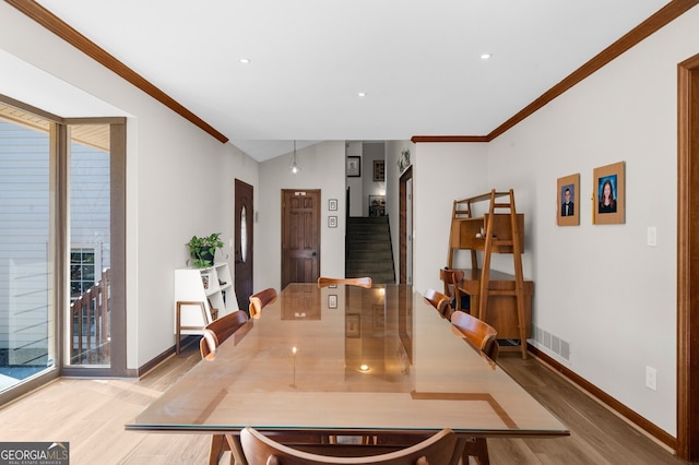 dining room with stairway, wood finished floors, baseboards, lofted ceiling, and ornamental molding