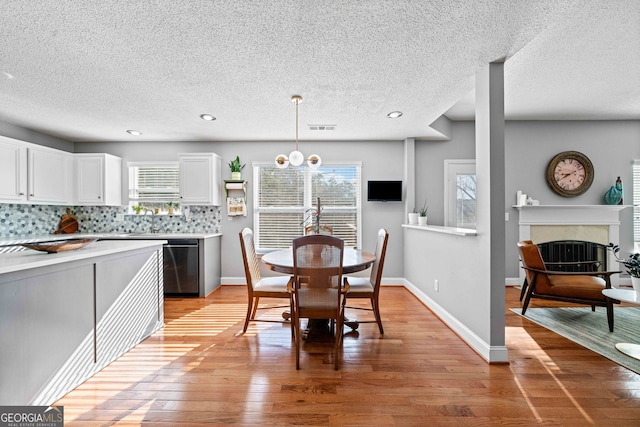 kitchen with stainless steel dishwasher, decorative backsplash, light countertops, and light wood-style floors