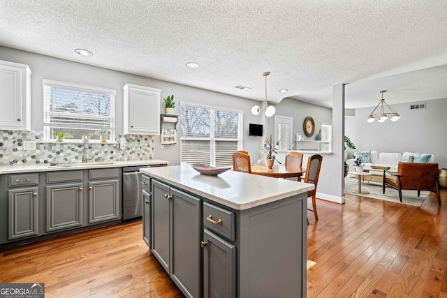 kitchen with visible vents, gray cabinetry, an inviting chandelier, white cabinets, and a sink