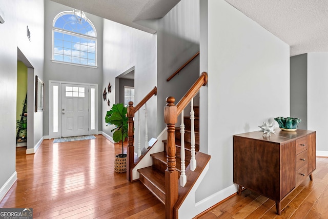 foyer entrance featuring hardwood / wood-style floors, baseboards, a wealth of natural light, and a textured ceiling