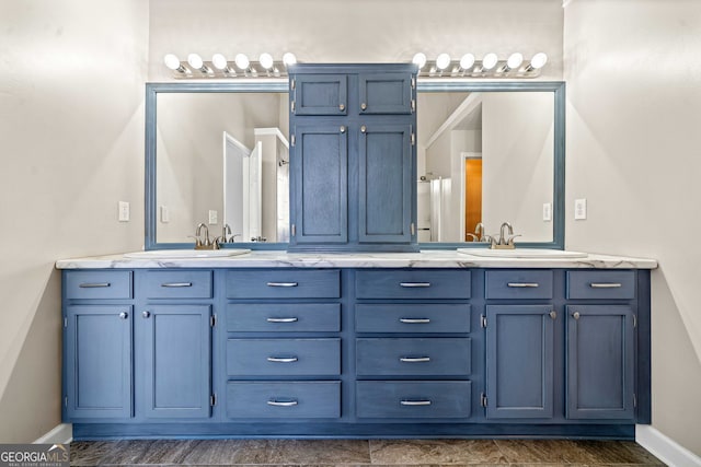 full bath featuring double vanity, baseboards, and a sink