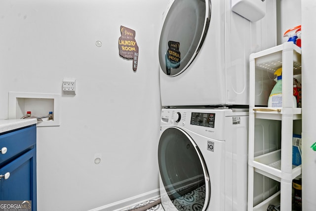 clothes washing area featuring laundry area, stacked washer / dryer, and baseboards
