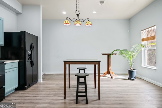 kitchen with light wood-type flooring, visible vents, black fridge with ice dispenser, recessed lighting, and baseboards
