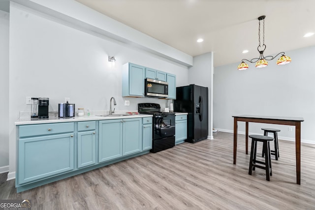 kitchen with blue cabinetry, light wood-type flooring, black appliances, and a sink