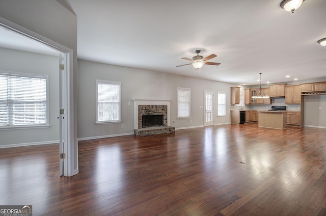 unfurnished living room featuring baseboards, a healthy amount of sunlight, dark wood-style flooring, and ceiling fan