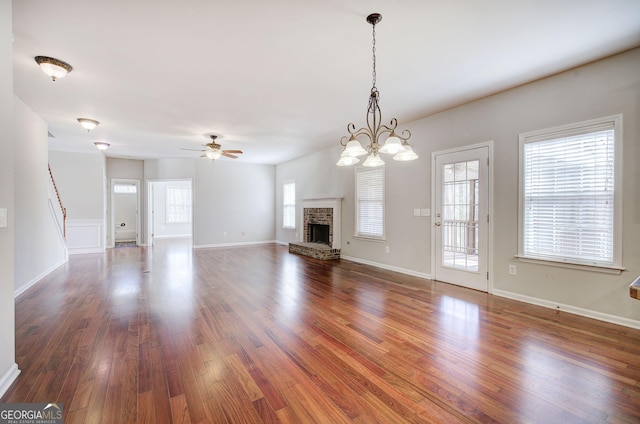 unfurnished living room featuring baseboards, stairs, a fireplace, wood finished floors, and a ceiling fan