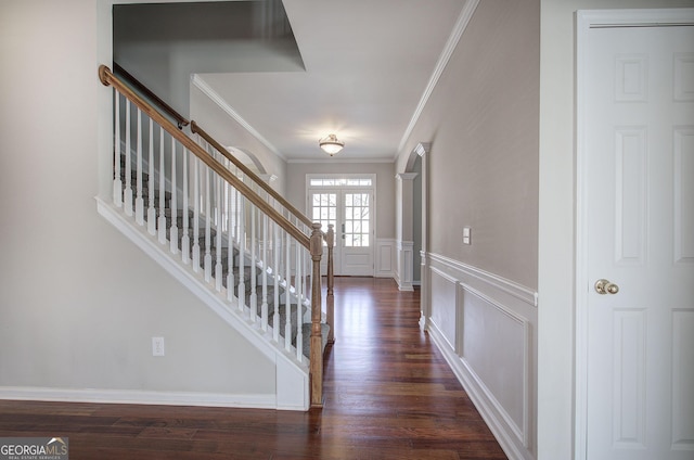 entryway with stairs, ornamental molding, wainscoting, a decorative wall, and dark wood-style flooring