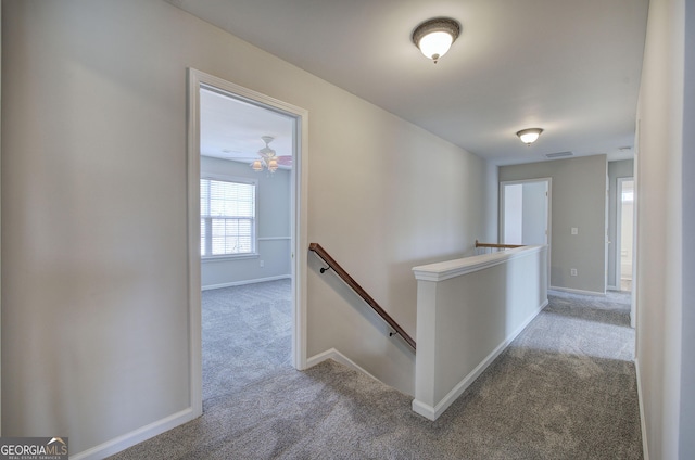 hall with an upstairs landing, carpet flooring, baseboards, and visible vents