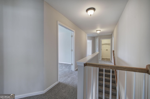 hallway with carpet flooring, an upstairs landing, and baseboards