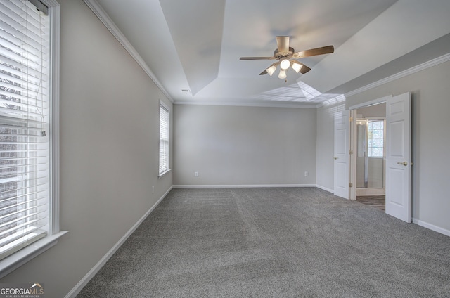 carpeted spare room with a tray ceiling, baseboards, a ceiling fan, and crown molding