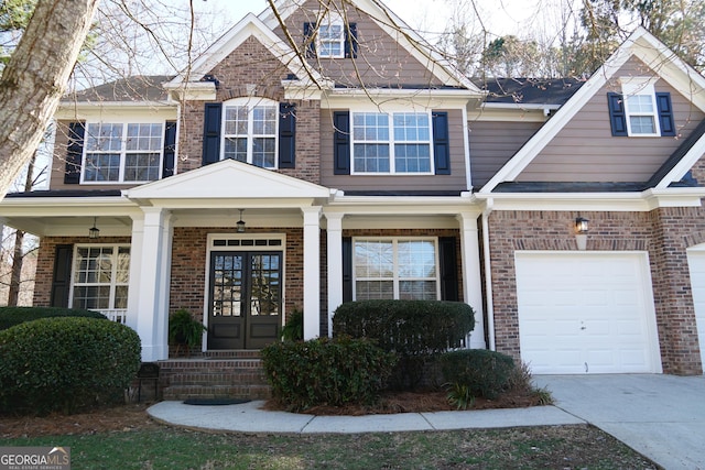 view of front of property featuring brick siding, concrete driveway, covered porch, french doors, and an attached garage