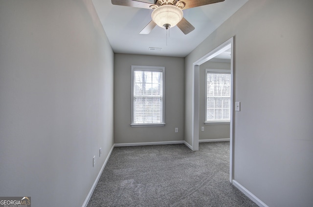 carpeted spare room with visible vents, a ceiling fan, and baseboards