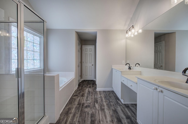 full bath featuring double vanity, a bath, wood finished floors, and a sink