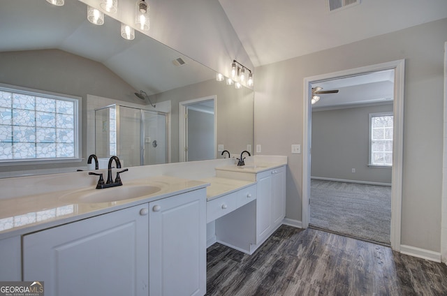 bathroom featuring double vanity, a sink, a shower stall, and vaulted ceiling