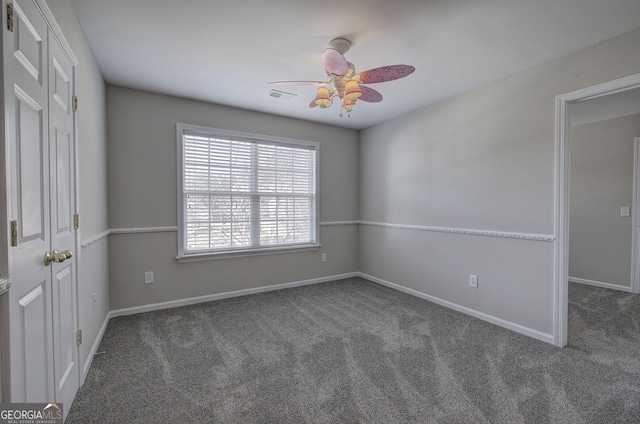 carpeted empty room with visible vents, baseboards, and a ceiling fan