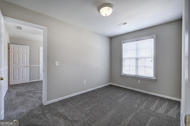 unfurnished room featuring visible vents, baseboards, and dark carpet