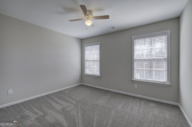 carpeted empty room featuring visible vents, baseboards, a healthy amount of sunlight, and ceiling fan