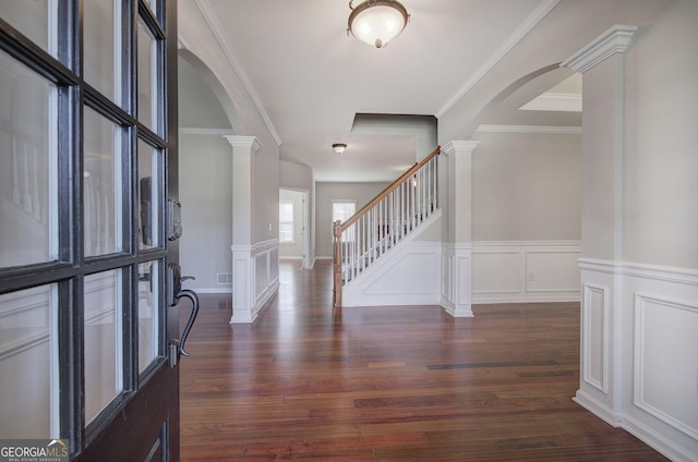 foyer entrance featuring arched walkways, stairway, dark wood-type flooring, and decorative columns