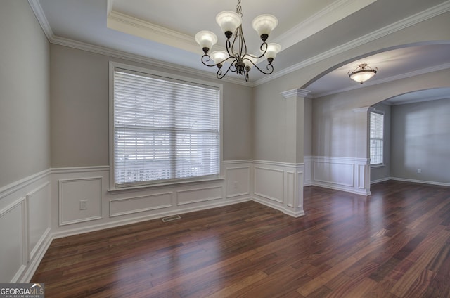 empty room featuring a tray ceiling, visible vents, arched walkways, and a chandelier