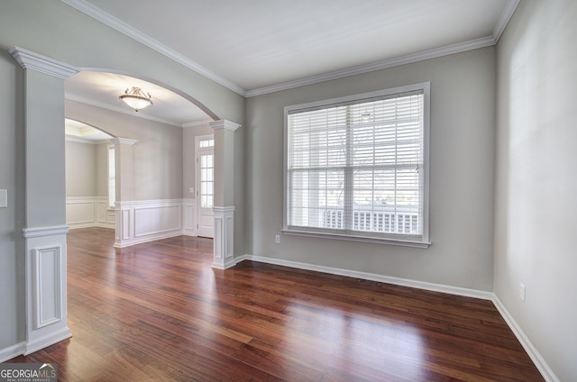 unfurnished room featuring crown molding, wainscoting, arched walkways, ornate columns, and dark wood-style flooring