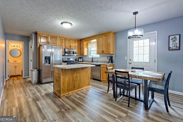95 Volunteer Ln, Murphy, NC 28906 - kitchen with backsplash, a kitchen island, light wood-type flooring, light countertops, and appliances with stainless steel finishes
