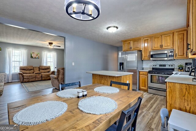95 Volunteer Ln, Murphy, NC 28906 - kitchen with light wood-type flooring, light countertops, decorative backsplash, stainless steel appliances, and a textured ceiling