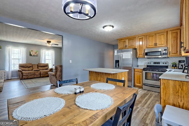 95 Volunteer Ln, Murphy, NC 28906 - kitchen featuring stainless steel appliances, light countertops, light wood-type flooring, backsplash, and brown cabinets