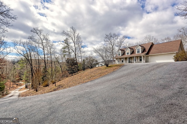 view of front of home featuring aphalt driveway, roof with shingles, and an attached garage