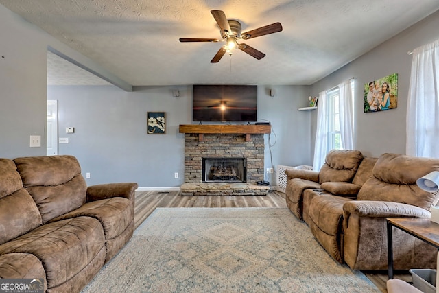 95 Volunteer Ln, Murphy, NC 28906 - living room featuring baseboards, a fireplace, wood finished floors, a textured ceiling, and a ceiling fan