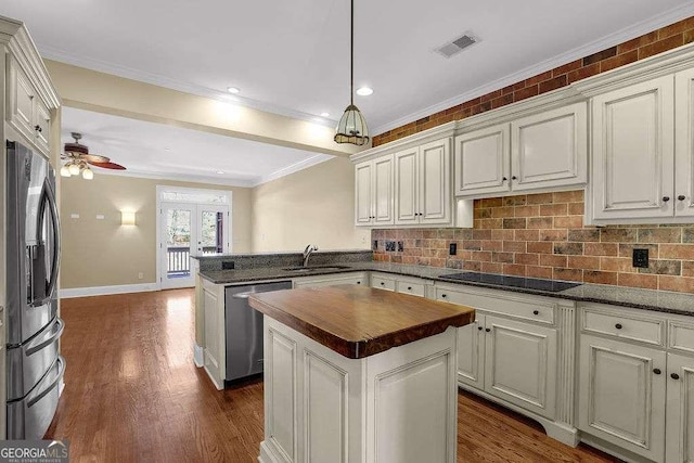 kitchen with a peninsula, dark wood-style flooring, a sink, stainless steel appliances, and wood counters