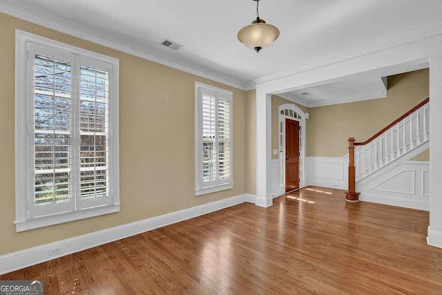 entryway with visible vents, a wainscoted wall, ornamental molding, wood finished floors, and stairs