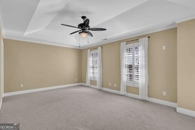 carpeted spare room with visible vents, crown molding, ceiling fan, baseboards, and a raised ceiling