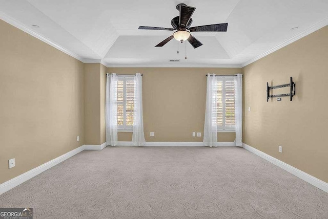 carpeted empty room featuring a healthy amount of sunlight, a raised ceiling, a ceiling fan, and ornamental molding