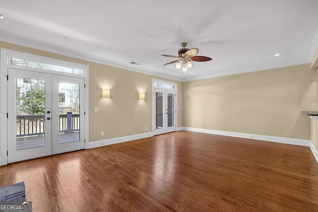 unfurnished living room with crown molding, wood finished floors, french doors, and baseboards