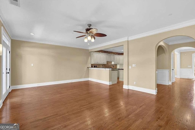 unfurnished living room with visible vents, ornamental molding, wood finished floors, arched walkways, and a ceiling fan