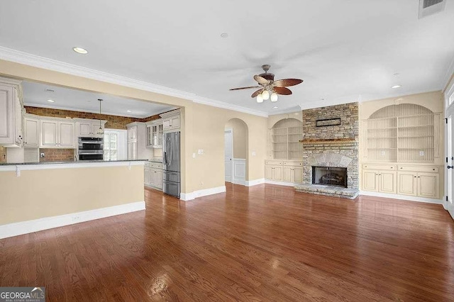 unfurnished living room featuring dark wood finished floors, a stone fireplace, visible vents, and ornamental molding