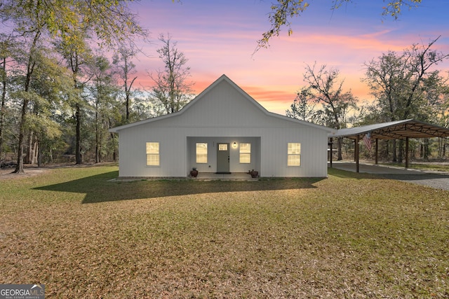 back of property at dusk featuring a carport and a yard