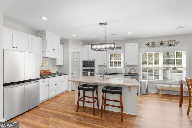 kitchen with white cabinetry, light wood-style floors, appliances with stainless steel finishes, and a sink