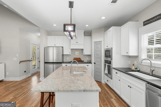 kitchen with a sink, white cabinets, wood finished floors, and stainless steel appliances