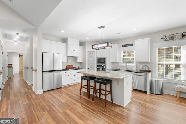 kitchen featuring a breakfast bar, light wood-style flooring, stainless steel appliances, white cabinetry, and a sink