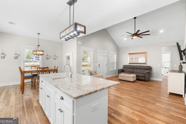 kitchen featuring a sink, light wood finished floors, hanging light fixtures, and white cabinetry