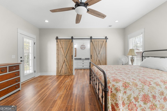 bedroom with access to outside, recessed lighting, a barn door, and wood finished floors