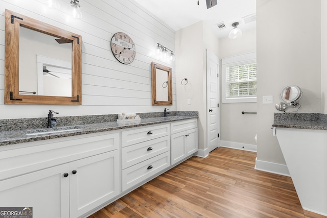 full bathroom featuring double vanity, visible vents, wood finished floors, and a sink