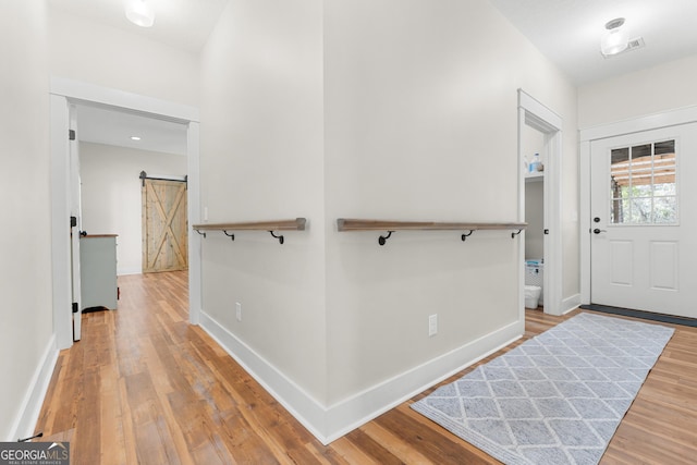 entryway featuring visible vents, baseboards, a barn door, and wood finished floors