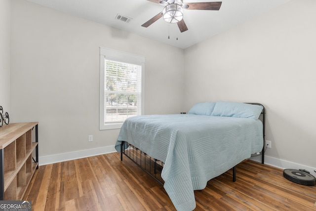 bedroom featuring ceiling fan, visible vents, baseboards, and wood finished floors